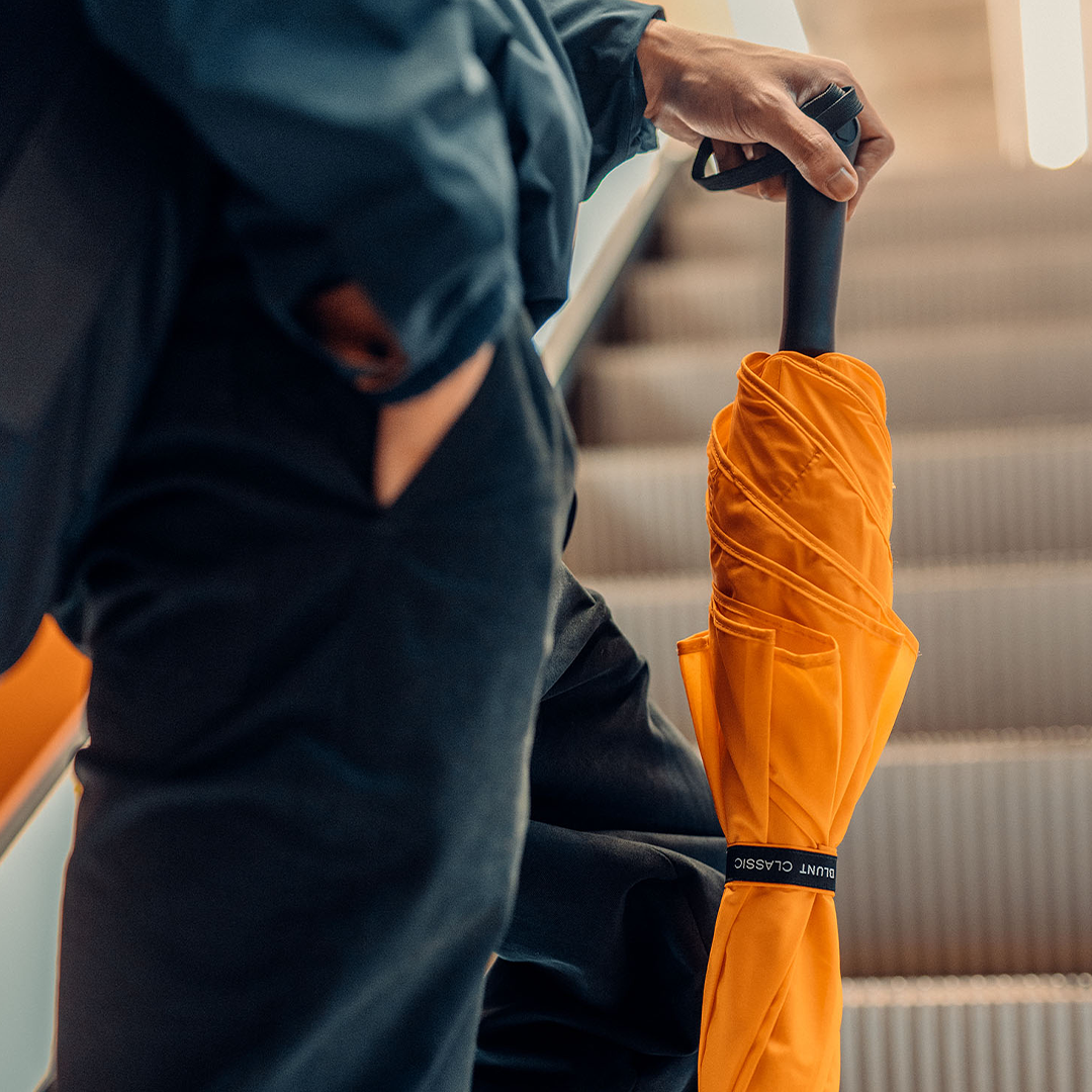 Man holding BLUNT Classic orange umbrella close up